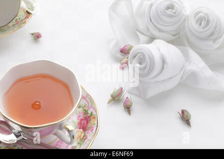 Rosa tea con fine bone china decorata con rose tovaglioli piegati Foto Stock