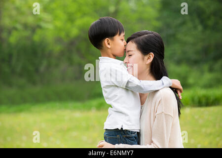 Little Boy baciando la sua madre sul fronte Foto Stock