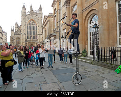 Street performer giocoleria con il fuoco su un monociclo guardato da turisti al di fuori Abbazia di Bath Bath, Inghilterra KATHY DEWITT Foto Stock