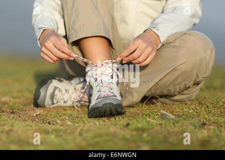 Escursionista donna lacci delle scarpe di legatura di scarponi con un background non focalizzato Foto Stock