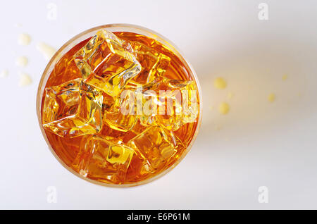 Vista dall'alto sulla bevanda alcolica in un bicchiere con cubetti di ghiaccio e la fuoriuscita di gocce sul tavolo Foto Stock