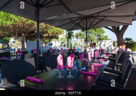 Fuori del ristorante tavoli sotto gli ombrelloni prevista per il servizio serale. Foto Stock