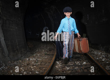 Bambino a camminare sulla strada ferrata con siutcase vintage. Foto Stock
