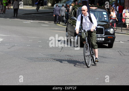 Un ciclista e taxi in viaggio a Londra Foto Stock