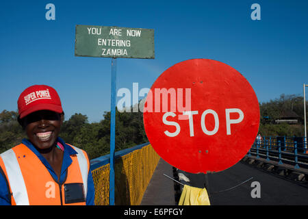 Una donna controlla il traffico tra Zambia e Zimbabwe. Un simbolo di arresto indica che stiamo entrando in Zambia. Oggi uno dei V Foto Stock