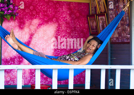 Donna rilassante in blu amaca, nel villaggio galleggiante di Chong Kos, sul Tonlé Sap fiume, vicino a Kampong Chhnang, Cambogia. Foto Stock