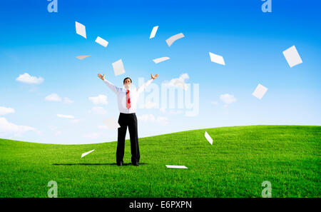 Business man sul campo con le braccia sollevate gettando Paperworks Foto Stock