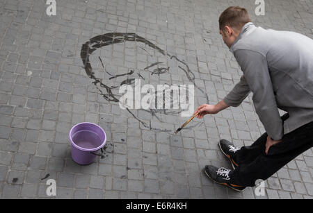 Gli attivisti prendere parte in un azione di arte di attirare l attenzione alla scomparsa forzata con i volti di persone scomparse, Juan Almonte Herrera (Repubblica Dominicana), dipinta in acqua sul marciapiede a Berlino, Germania, 29 agosto 2014. Amnesty International è richiamare l attenzione alle vittime di scomparsa forzata. Ogni anno migliaia di persone in tutto il mondo vengono catturati e portati a luoghi sconosciuti su stato ordini o in cooperazione con lo stato. Foto: JOERG CARSTENSEN/dpa Foto Stock