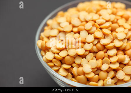 Split piselli gialli in una ciotola di vetro su sfondo nero Foto Stock