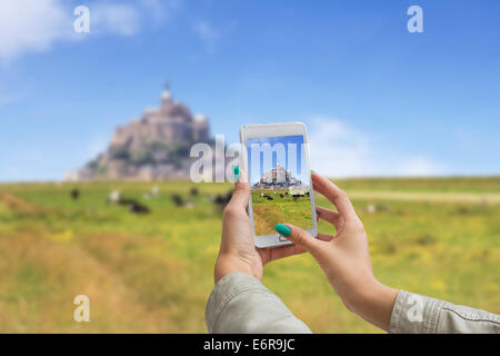 Ragazza di scattare le foto su un telefono cellulare, Le Mont Saint Michel Abbey, Normandia / Brittany, Francia Foto Stock