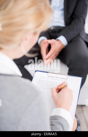 Psicologo femmina rendendo note durante terapia psicologica sessione Foto Stock