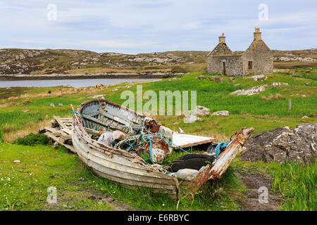 La scena delle Ebridi con la vecchia barca da pesca e abbandonata croft cottage nel paesaggio scozzese di Loch Sgioport, Sud Uist, Ebridi Esterne, Scotland, Regno Unito Foto Stock