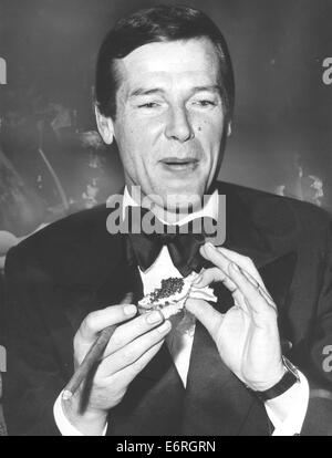 Jan 18, 1975 - Monaco di Baviera, Germania - Sir Roger George Moore KBE (nato il 14 ottobre 1927) è un attore inglese. Egli è forse più noto per la riproduzione di agente segreto britannico James Bond nel film ufficiale serie per sette pellicole tra 1973 e 1985. Egli è apparso come legame in più ufficiale di film di James Bond rispetto a qualsiasi altro attore ed è il più antico attore per giocare Bond. Moore raffigurata anche Simon Templar nel Saint dal 1962 al 1969. Egli è anche un ambasciatore di benevolenza per l'organizzazione di beneficenza UNICEF. Nella foto: Roger Moore con un sigaro e caviale su toast al annuale "Filmball 75' gala tenutosi presso la Bayerischer Ho Foto Stock