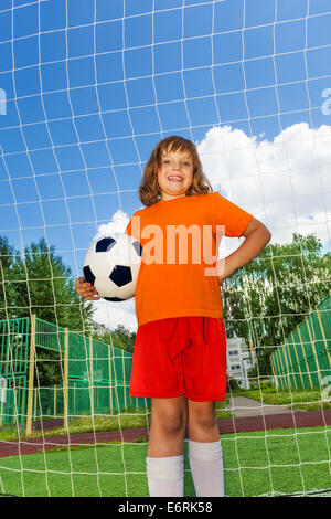 Ragazza di Felice Tiene il calcio in piedi vicino al bianco net Foto Stock