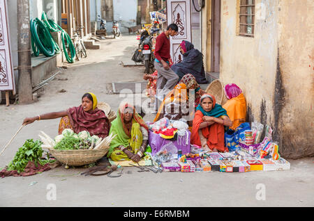 Locali di donne abbigliate in sari sedersi sul ciglio della strada la vendita di verdura, hardware e bric-a-brac, Deogarh, Rajasthan, India Foto Stock