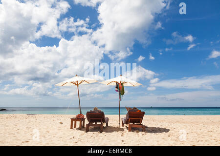 Sedie a sdraio e due sole Ombrelloni sulla spiaggia sabbiosa a Pansea Beach, Phuket, Thailandia con cielo blu e bianchi e soffici nuvole Foto Stock