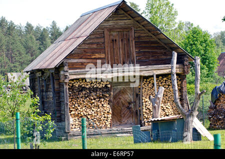 Vecchio capanno in legno con legna da ardere in villaggio Foto Stock