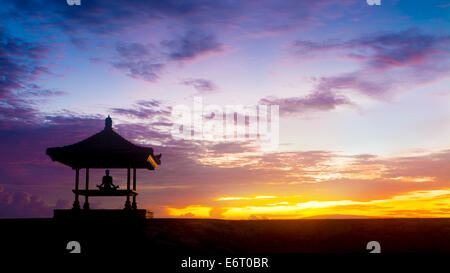 Meditazione yoga outdoor sotto il gazebo in piena lotus posizione presso la spiaggia su all'alba o al tramonto. Concetto di mindfulness, pacifica e travlling a Bali Foto Stock