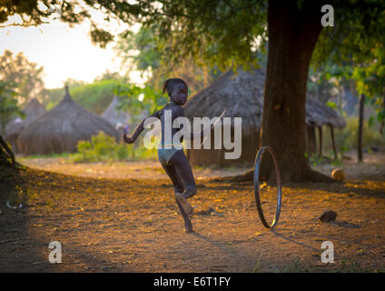 Anuak bambino ragazza che gioca con una ruota in Abobo, ex re Anuak Village, regione di Gambela, Etiopia Foto Stock
