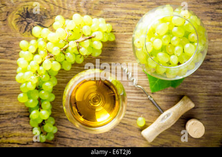 Bicchiere di vino bianco e un grappolo di uva, un apribottiglie, sughero. La vista dall'alto. Foto Stock