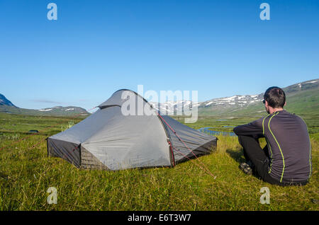 Un uomo seduto da solo vicino alla sua tenda in montagna sul Kungsleden (King's Trail), in Lapponia svedese Foto Stock