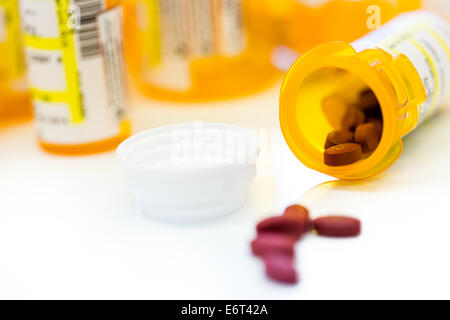Pillole di prescrizione in bottiglie di colore giallo su sfondo bianco. Foto Stock
