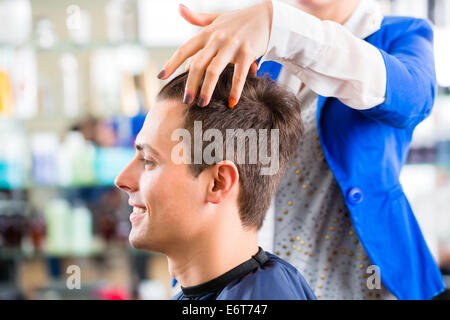 Coiffeur donna il taglio di capelli di uomini in parrucchiere Foto Stock