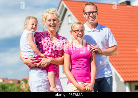 Una famiglia di genitori e figli orgogliosi in piedi di fronte a casa Foto Stock