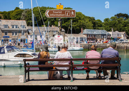 I turisti seduta su una panchina e si affaccia sul porto a Padstow, Cornwall, Regno Unito Foto Stock