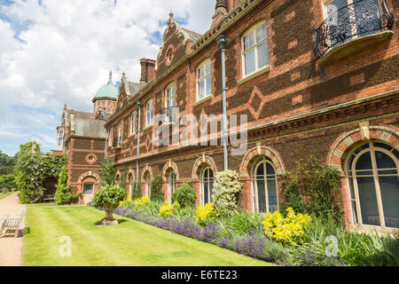 La facciata posteriore di Sandringham House, Queen's Norfolk country house retreat, con fine rosso mattone cotto e i confini dei fiori, in estate Foto Stock