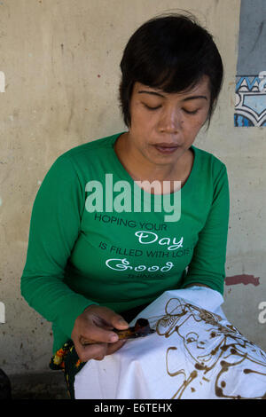 Yogyakarta, Java, Indonesia. La produzione di batik. Donna con cera calda per delineare un disegno su un panno Batik. Foto Stock