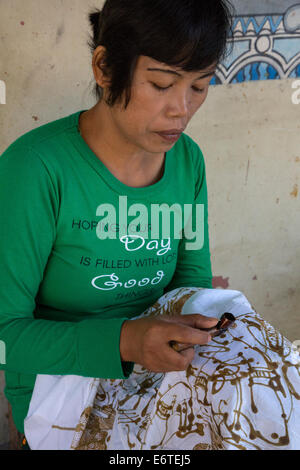 Yogyakarta, Java, Indonesia. La produzione di batik. Donna con cera calda per delineare un disegno su un panno Batik. Foto Stock