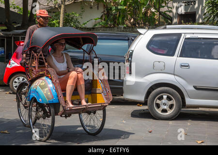 Yogyakarta, Java, Indonesia. Il passeggero in sella a un becak, un veicolo a tre ruote Powered by la propulsione umana. Foto Stock