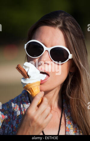 Una giovane donna di mangiare un gelato in Hyde Park in estate Foto Stock