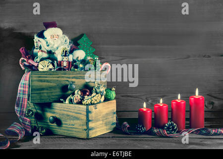 Masterizzazione di quattro candele di Natale con Babbo Natale e il vecchio avvento decorazione su legno. Foto Stock