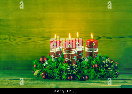 Tradizionale corona di Avvento o la corona con quattro red candele accese su sfondo di legno. Foto Stock