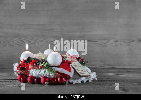 Secondo Avvento: due candele accese decorate in bianco e rosso di legno su sfondo grigio. Foto Stock