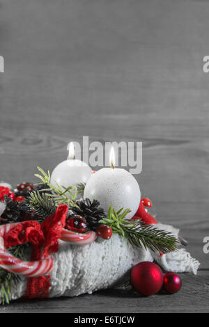Secondo Avvento: rosso due candele accese su legno malandata sfondo grigio. Foto Stock