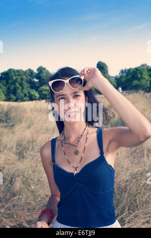 Una giovane donna con capelli castani nel suo ventenne rilassante in Hyde Park e i Kensington Gardens a Londra in estate Foto Stock