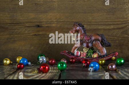 Colorato sfondo di Natale con un cavallo a dondolo e vecchie sfere. Foto Stock