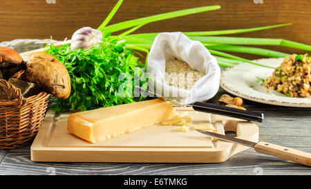 Gli ingredienti di italiano il risotto con funghi disposti su una tavola di legno Foto Stock