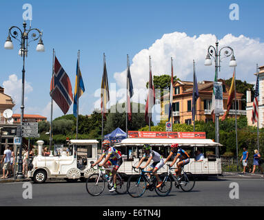 Tre i ciclisti in Piazza Tasso, Sorrento, passando un autobus turistico progettato per assomigliare ad un piccolo treno. Foto Stock