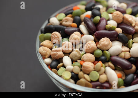 Fagioli misti in una ciotola di vetro su sfondo nero. Close-up. Foto Stock