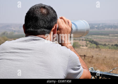 Alture del Golan, Israele. 31 Agosto, 2014. Un uomo di vedute di città siriane di Quneitra dal lato Israeliano del confine, nella zona dove Jabat anteriore Al-Nusra rapito più di due dozzine di peacekeepers delle Nazioni Unite. Credito: Nir Alon/Alamy Live News Foto Stock