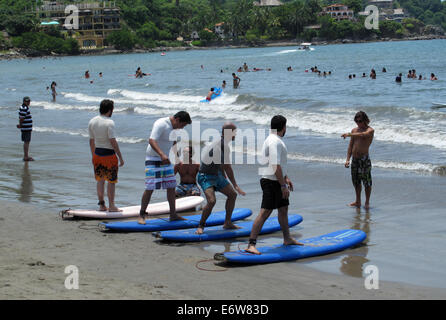 Gli uomini in piedi sulla tavola da surf in spiaggia durante una lezione di surf in Sayulita, Messico. Foto Stock