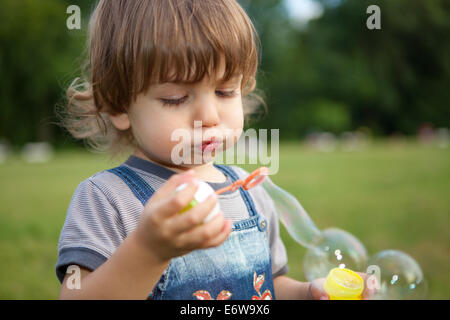 Little Boy soffia bolle di sapone nel parco. Foto Stock