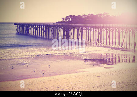 Vintage ponte di legno in spiaggia al tramonto, California, USA. Foto Stock