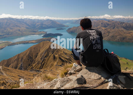 Escursionista godendo le viste da Mt Roy oltre il lago Wanaka, Isola del Sud, Nuova Zelanda Foto Stock