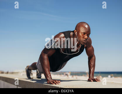 Atletica Giovane uomo che fa push-up. Modello di fitness facendo allenamento all'aperto. Muscoloso e forte ragazzo di esercizio. Foto Stock