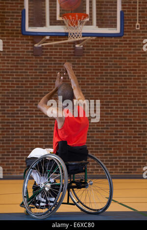 L'uomo con la meningite spinale in carrozzella giocare a basket Foto Stock